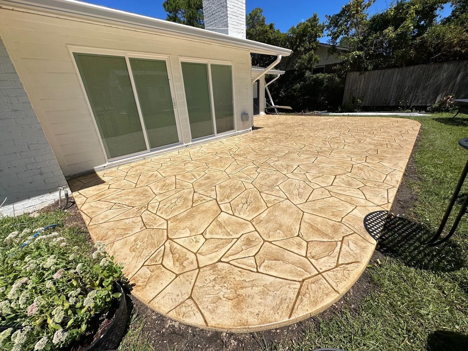 There is a concrete patio in the backyard of a house.