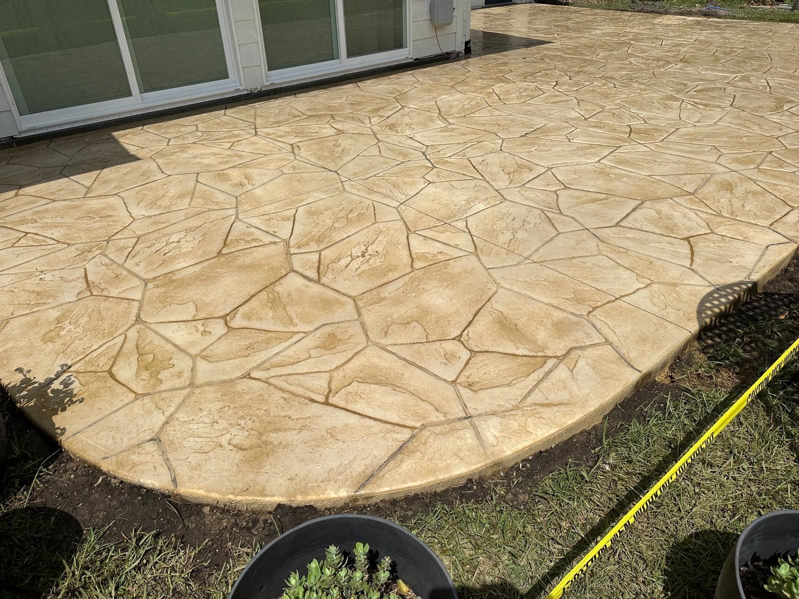 A concrete patio with a yellow tape measure next to it.