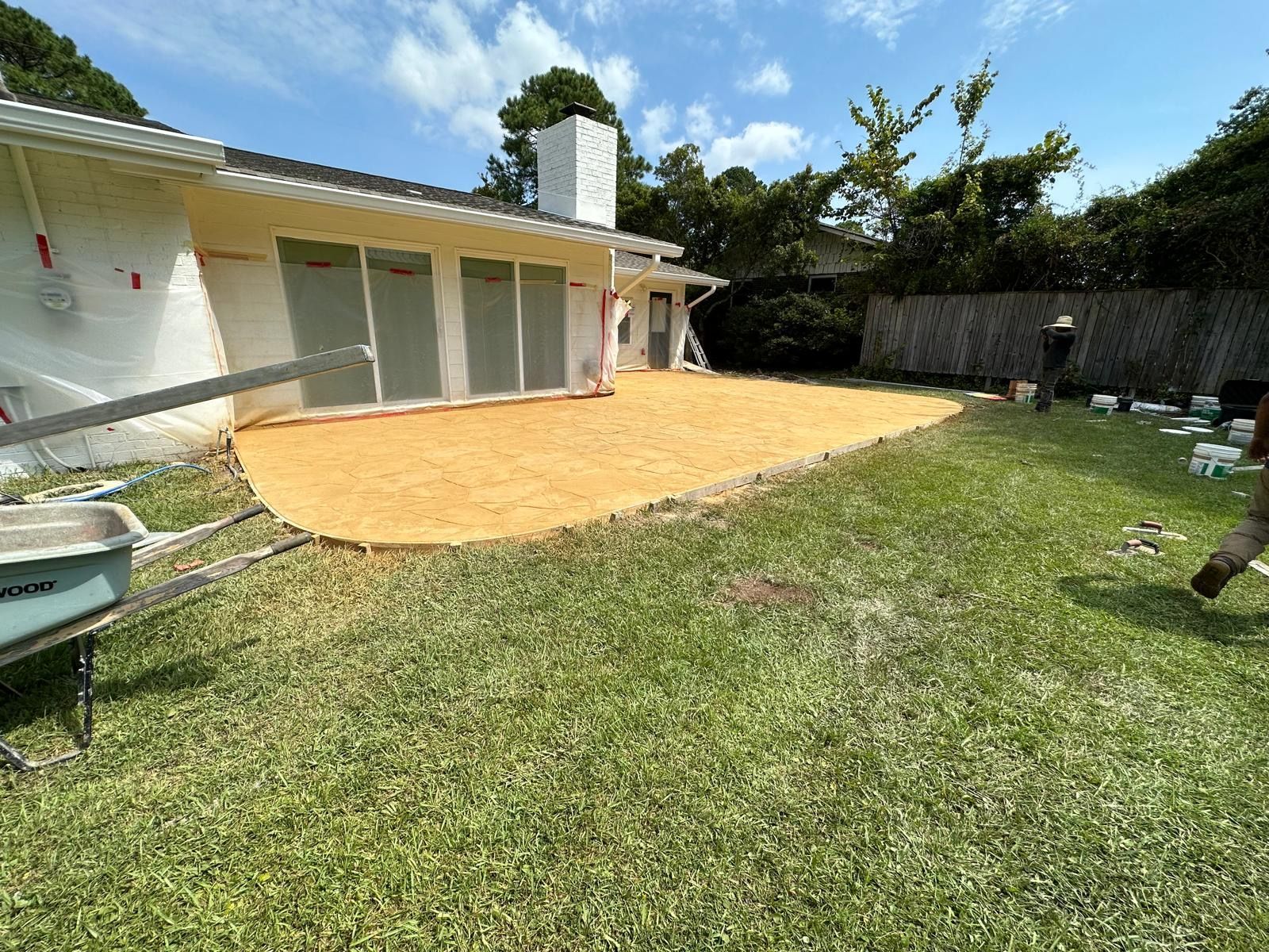 A wheelbarrow is sitting in the grass in front of a house.