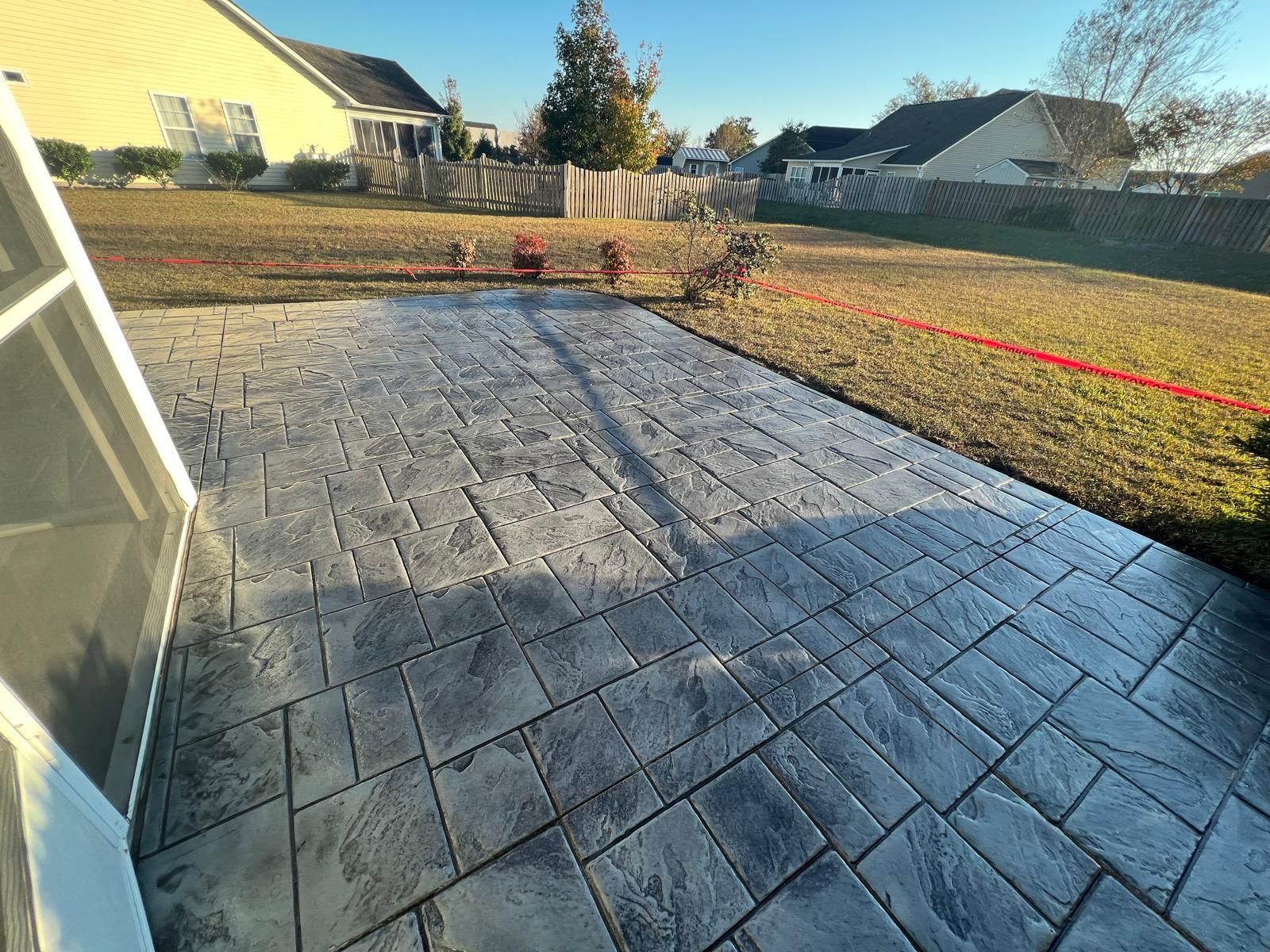 A concrete patio in a backyard with a house in the background.