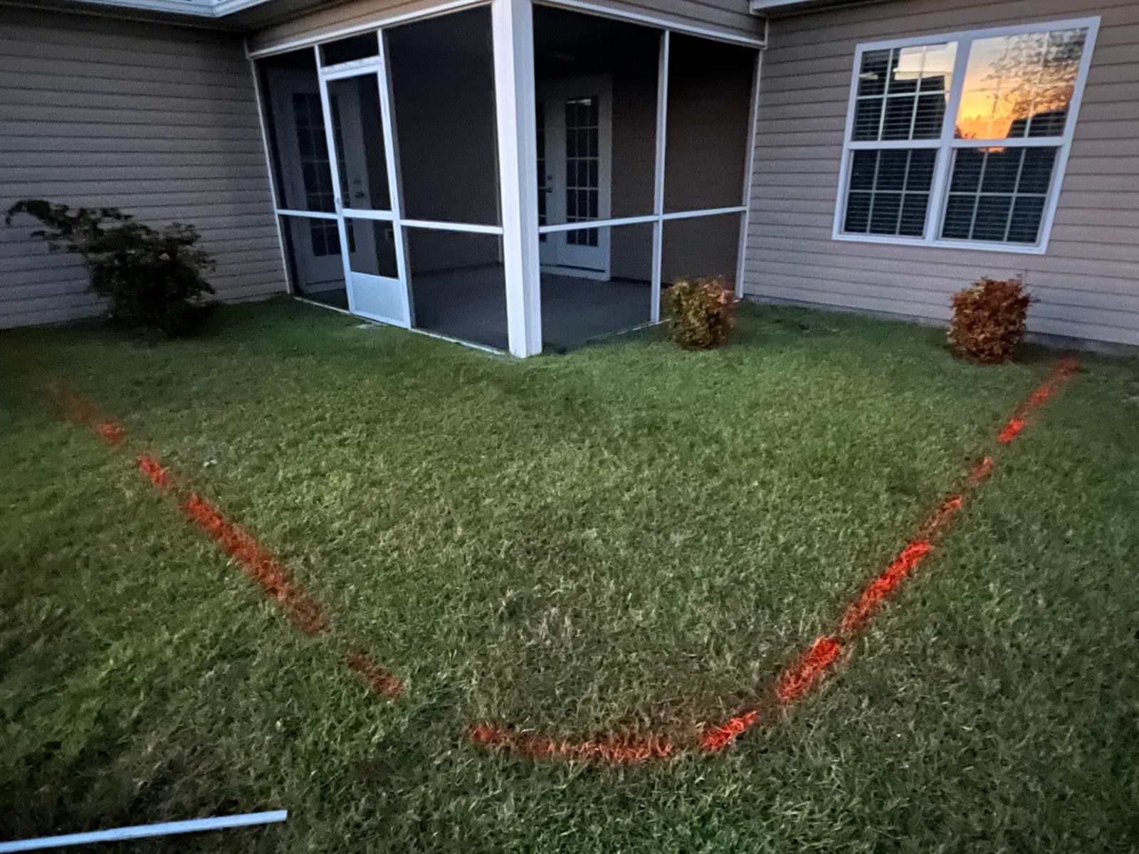 A house with a screened in porch and a red line in the grass