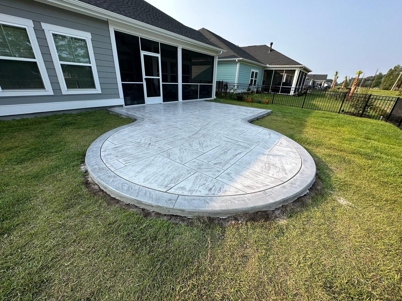 There is a circular patio in the backyard of a house.