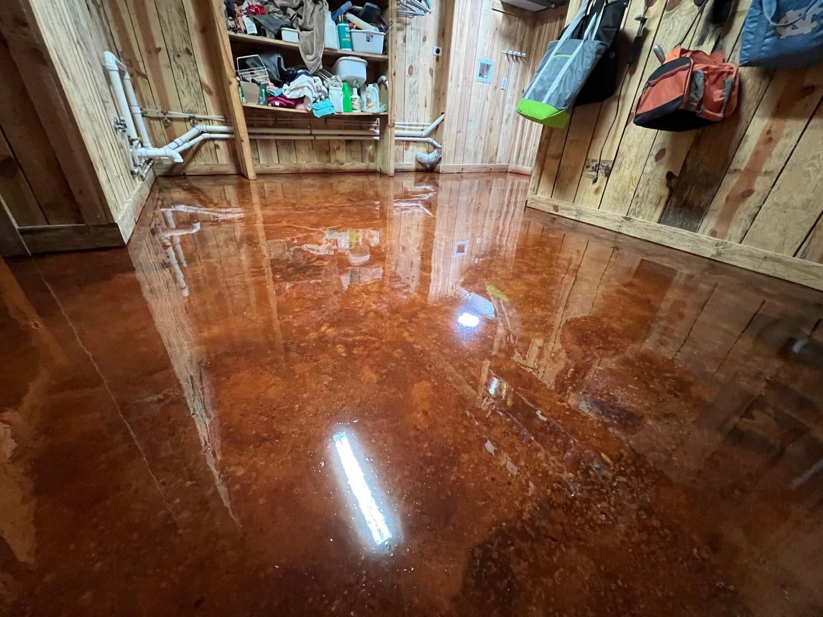 A room with a shiny concrete floor and a wooden wall.