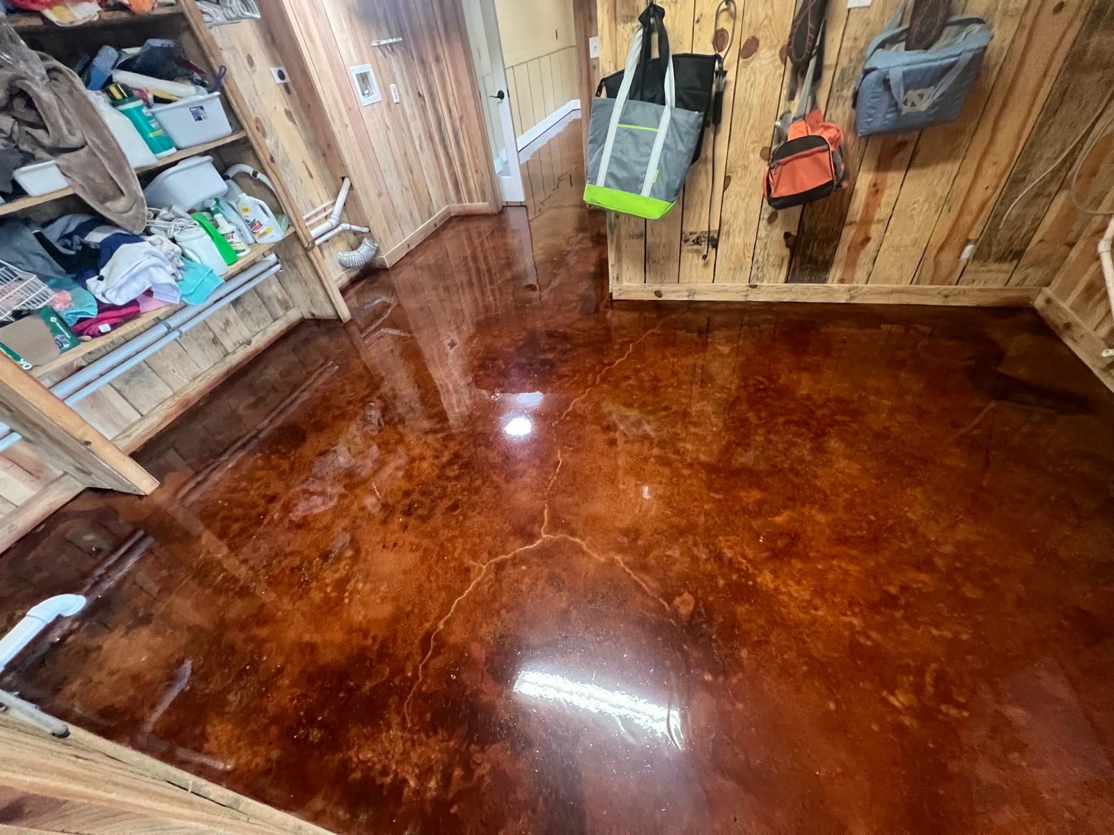A room with a stained concrete floor and wooden walls.