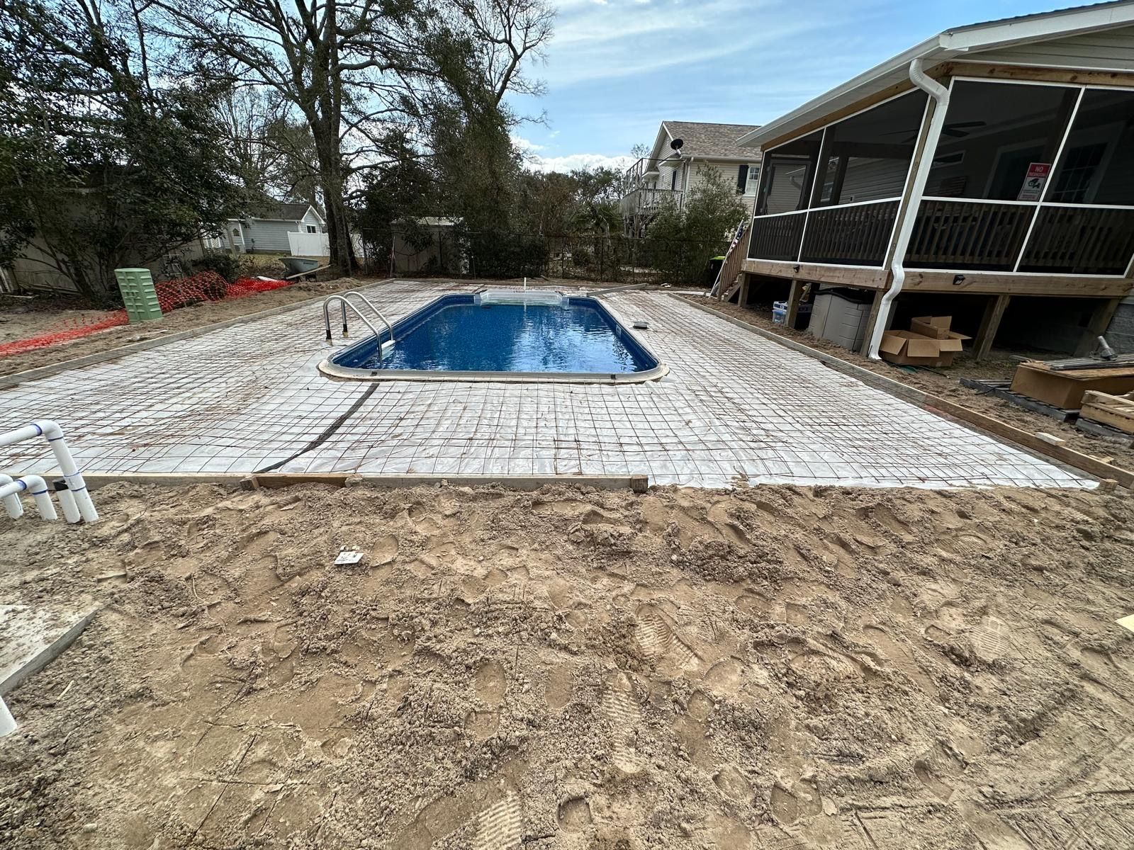 A large swimming pool is being built in the backyard of a house.