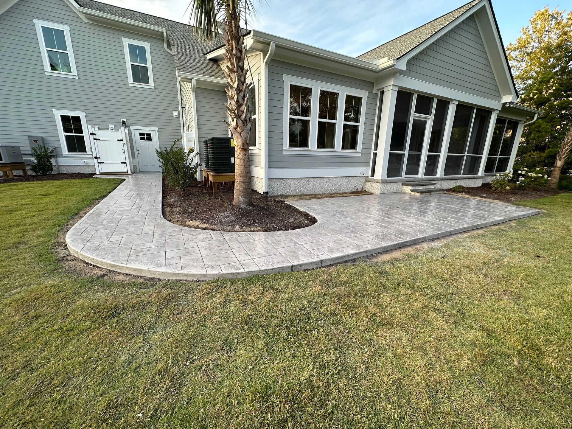 A large house with a screened in porch and a patio in front of it.