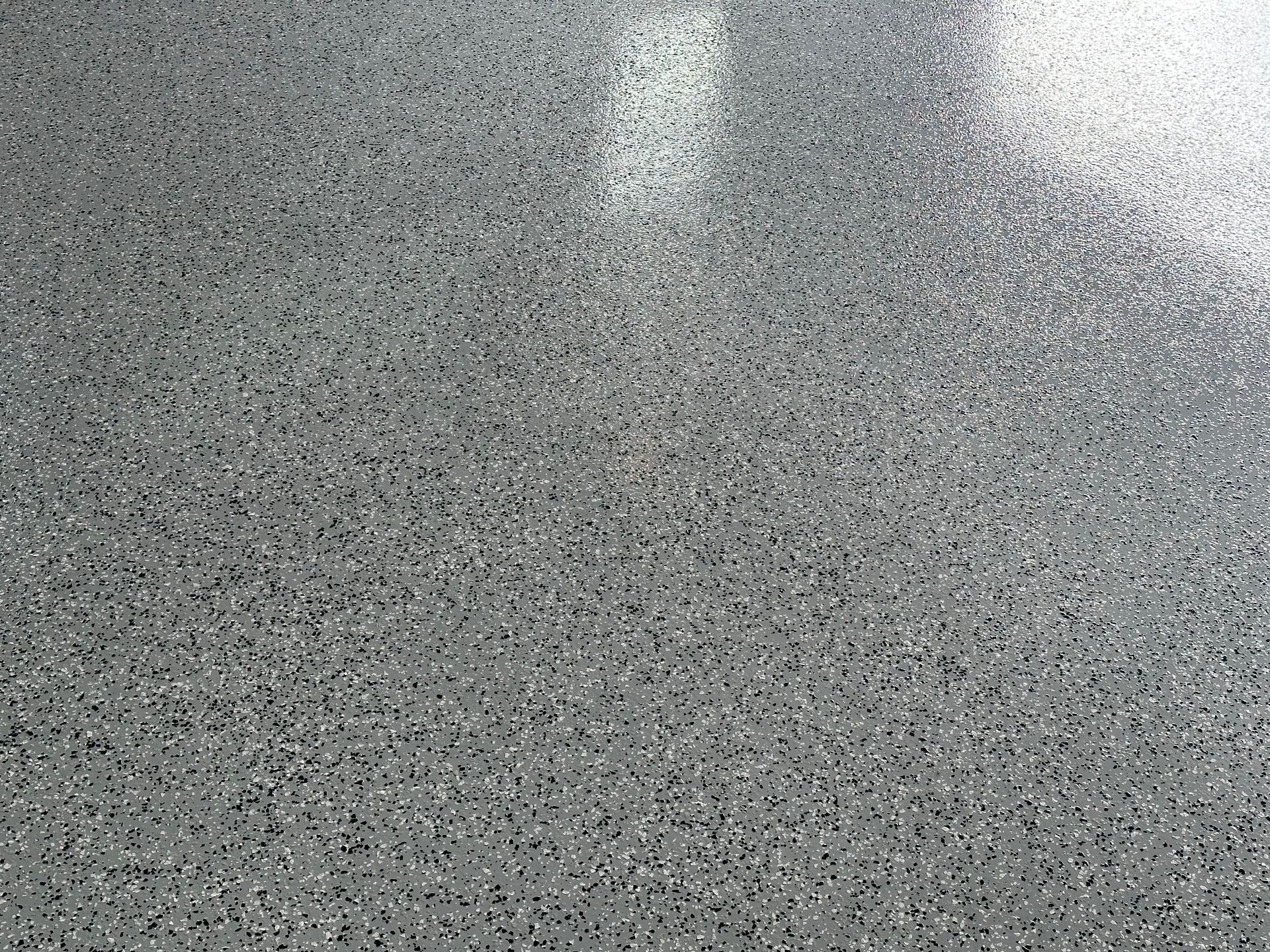 A close up of a gray concrete floor with a lot of small stones on it.
