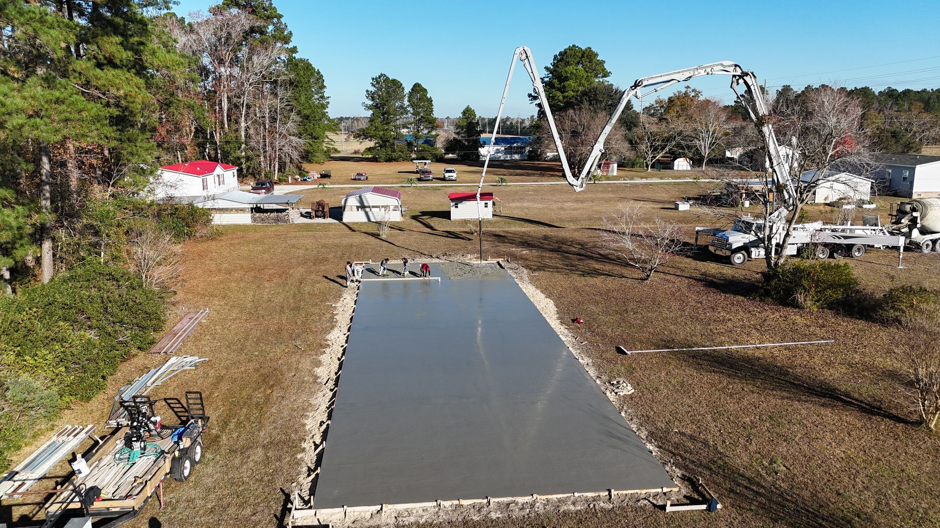 An aerial view of a large concrete slab being poured in a field.