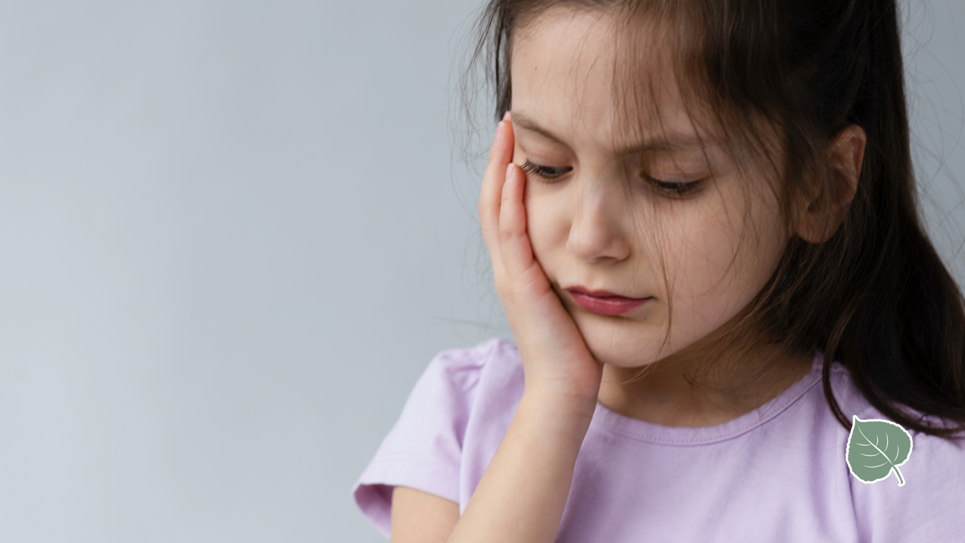 A little girl is holding her face with her hand.