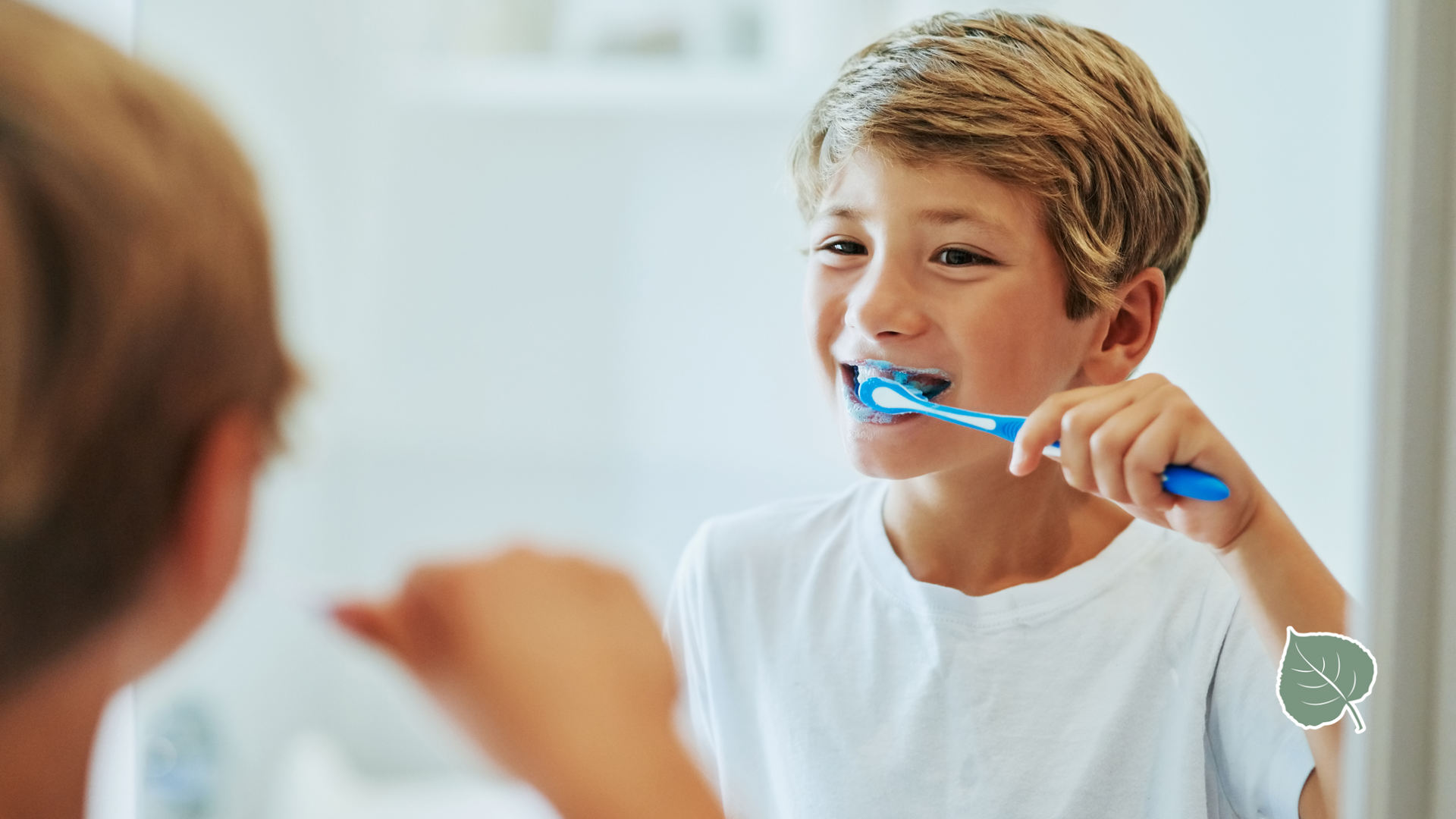 A young boy is brushing his teeth in front of a mirror.
