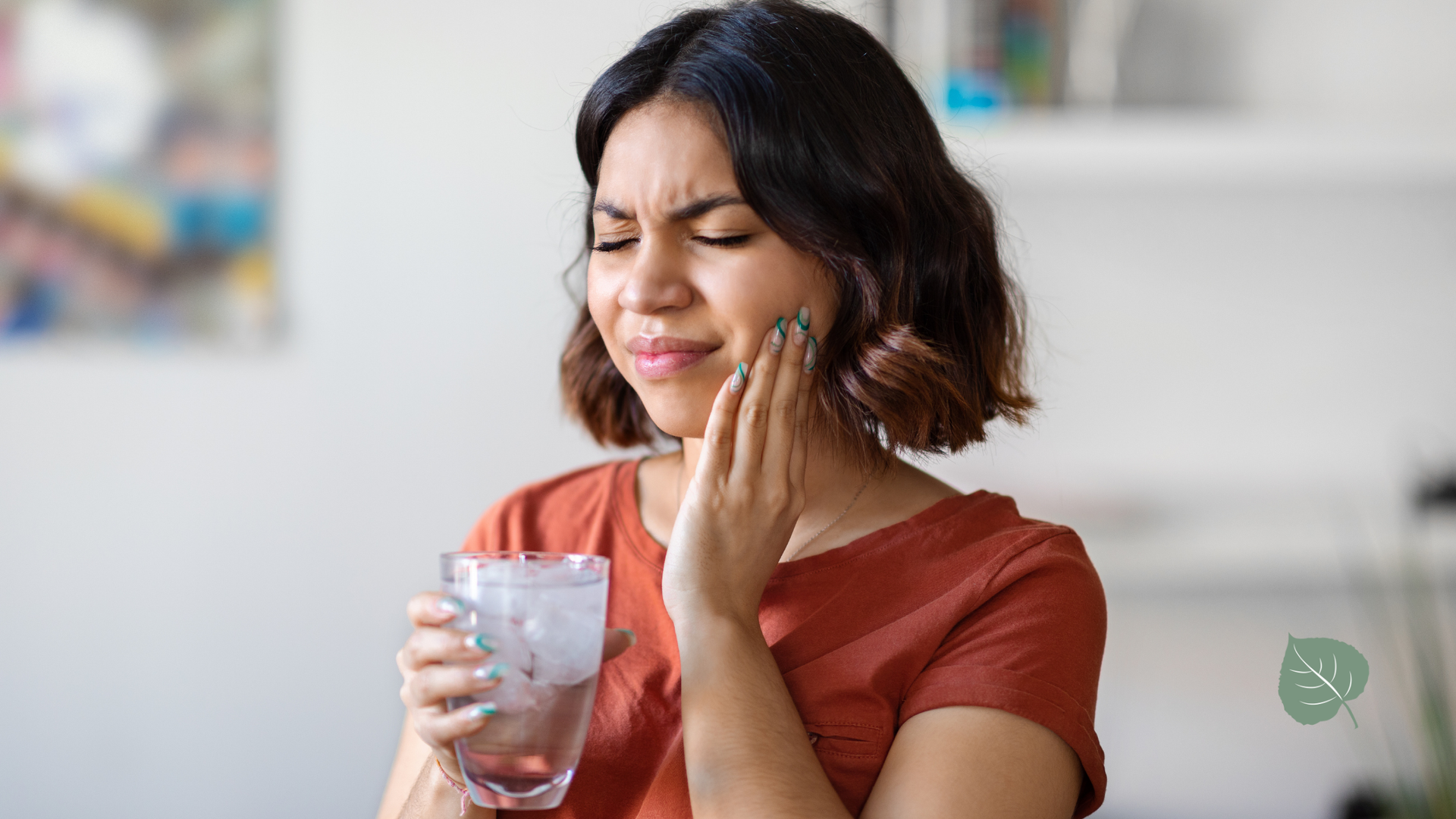 A woman is holding a glass of water and having a toothache.