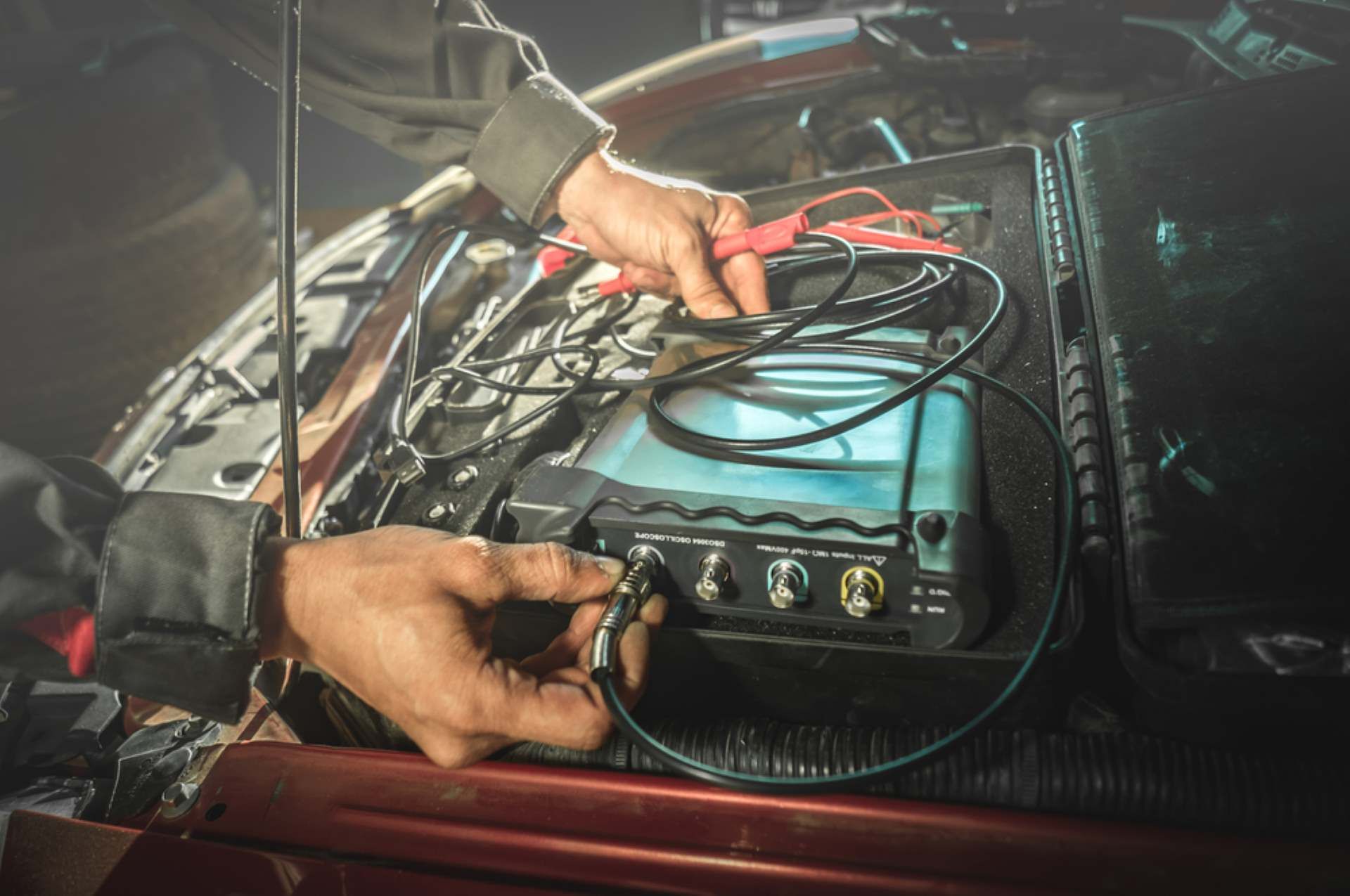 A Man is Working on a Car Battery With a Tester — Fraser Mobile Auto Tech in Tablelands, QLD
