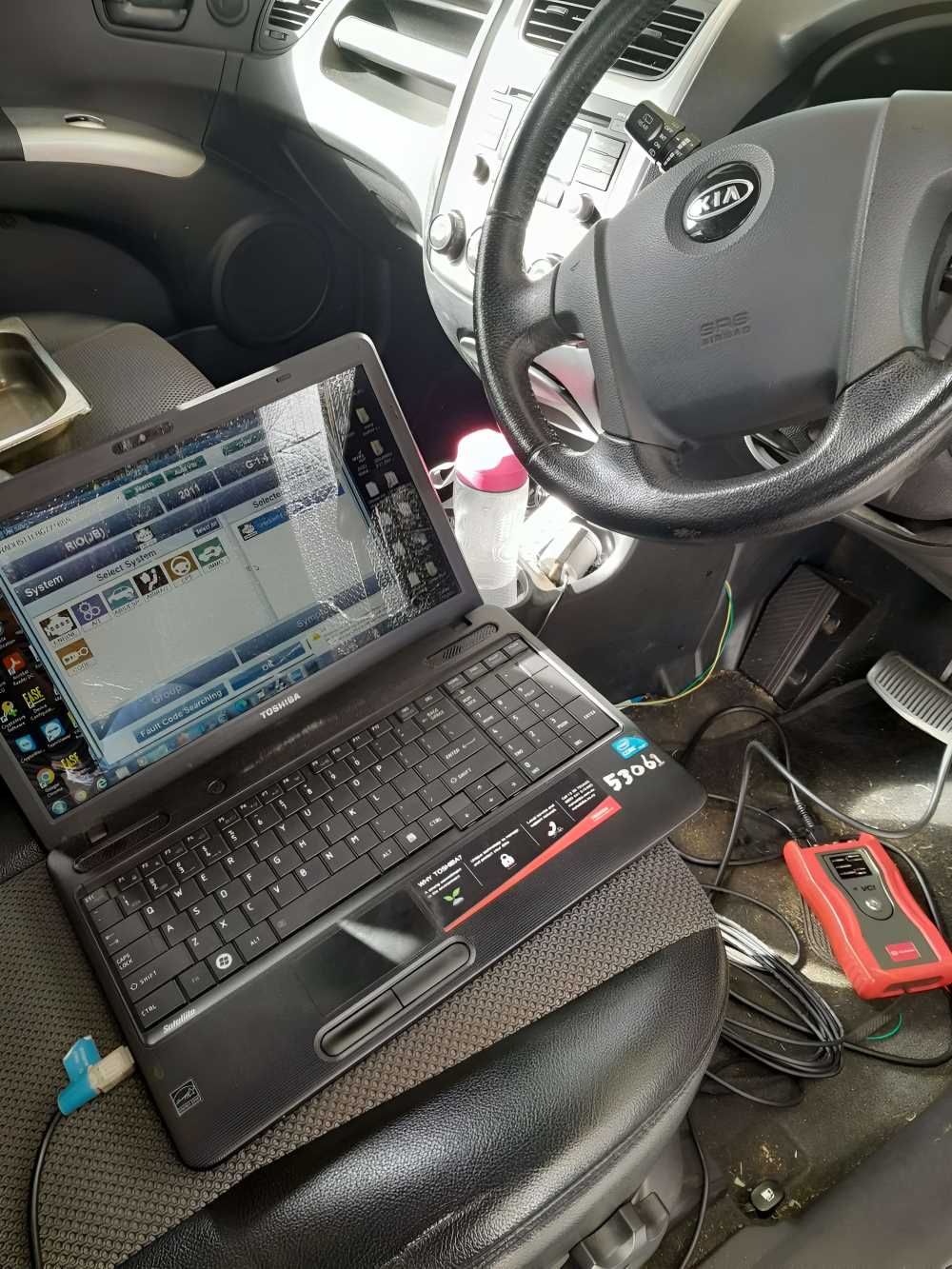 A Laptop is Sitting on a Car Seat Next to a Steering Wheel — Fraser Mobile Auto Tech in Tolga, QLD
