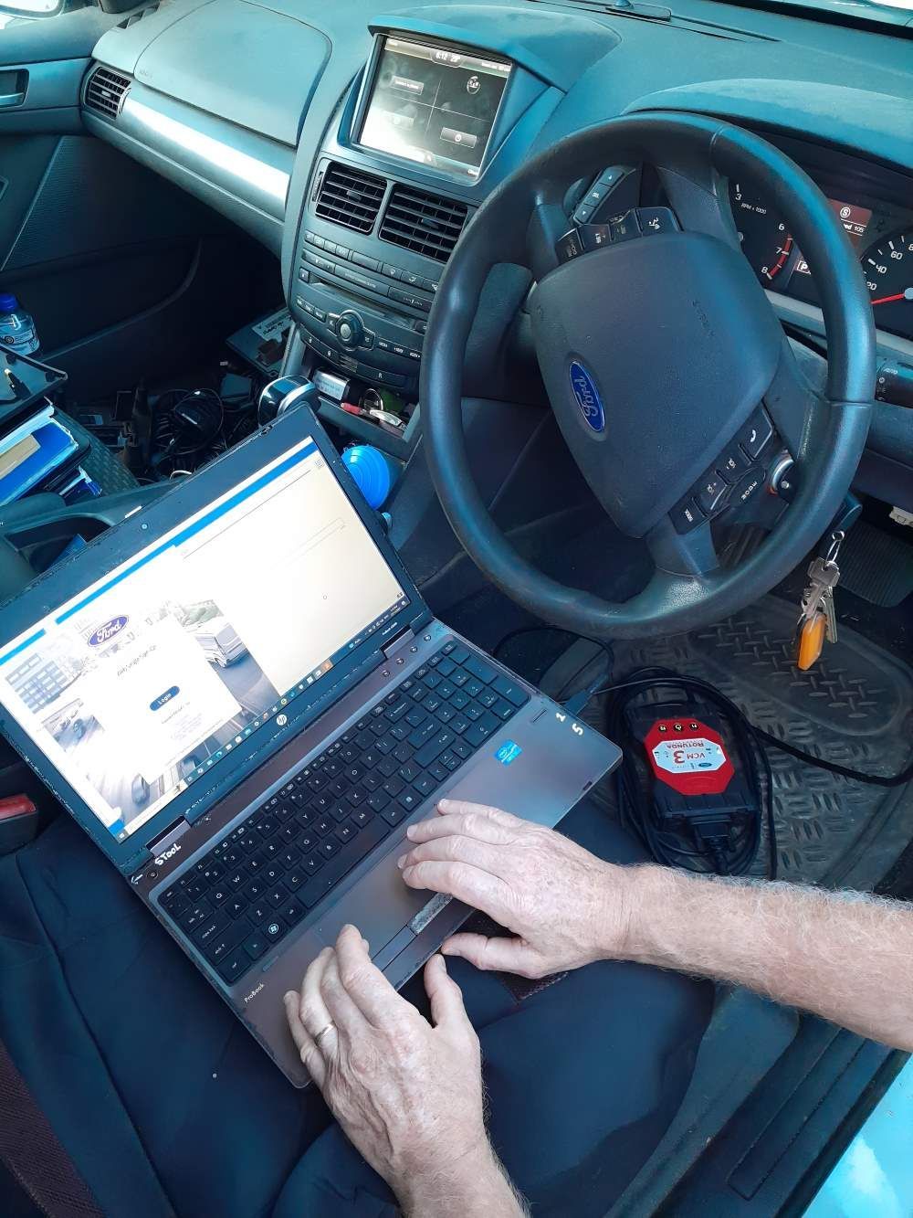 A Person is Typing on a Laptop in a Car — Fraser Mobile Auto Tech in Tolga, QLD