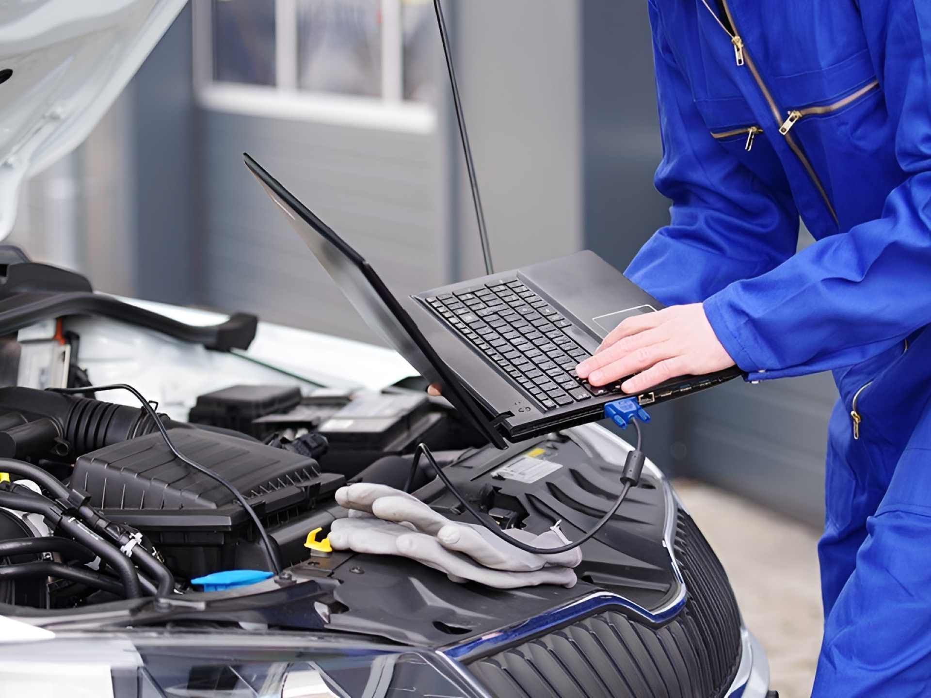 A Mechanic is Working on a Car With a Laptop — Fraser Mobile Auto Tech in Tolga, QLD
