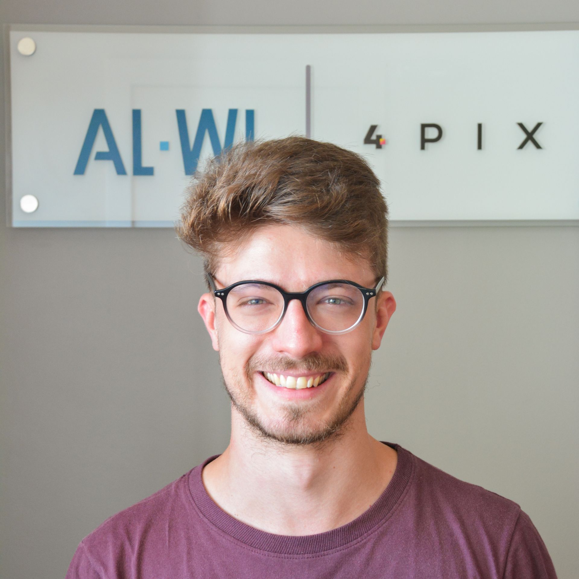 Um homem de óculos está sorrindo na frente de uma placa que diz al-wi 4 pix