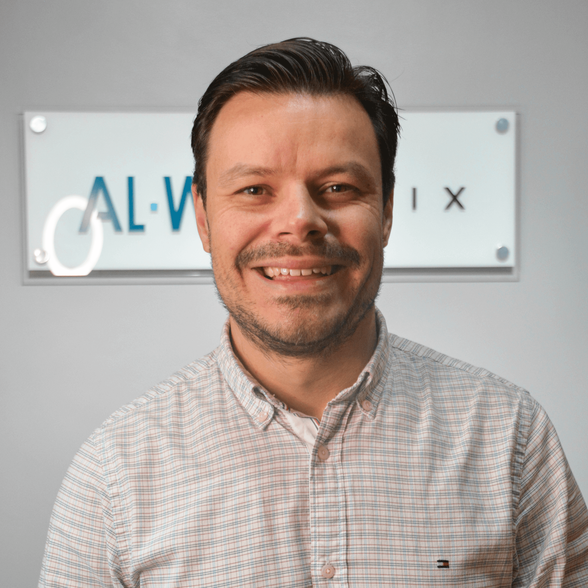 Um homem está sorrindo na frente de uma placa que diz cal-v-ix