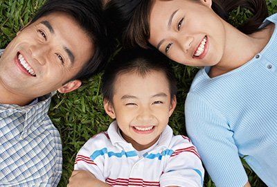 Couple with son lying on grass — Family Dentistry in Gurnee, IL