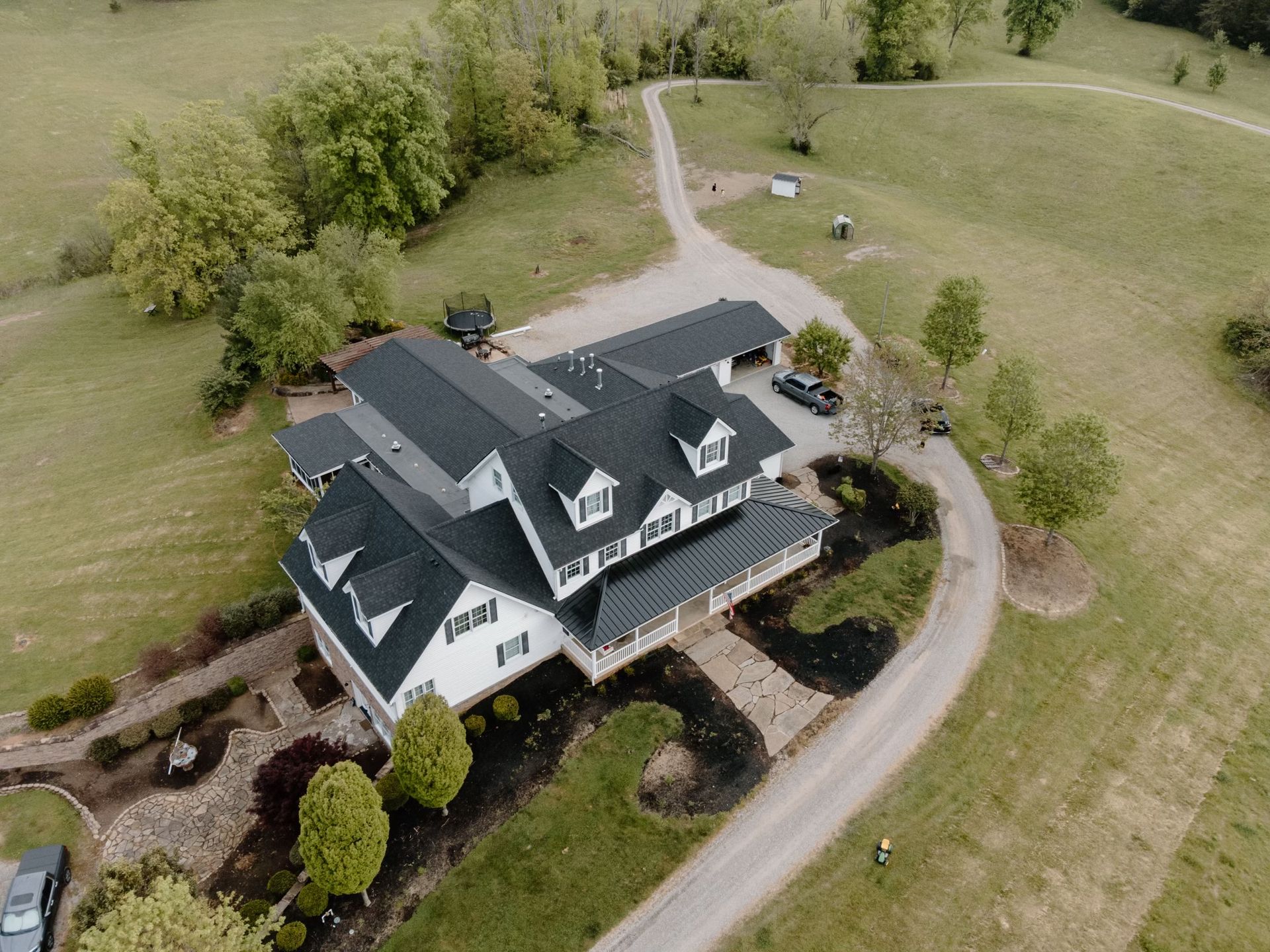 An aerial view of a large house surrounded by trees and grass.