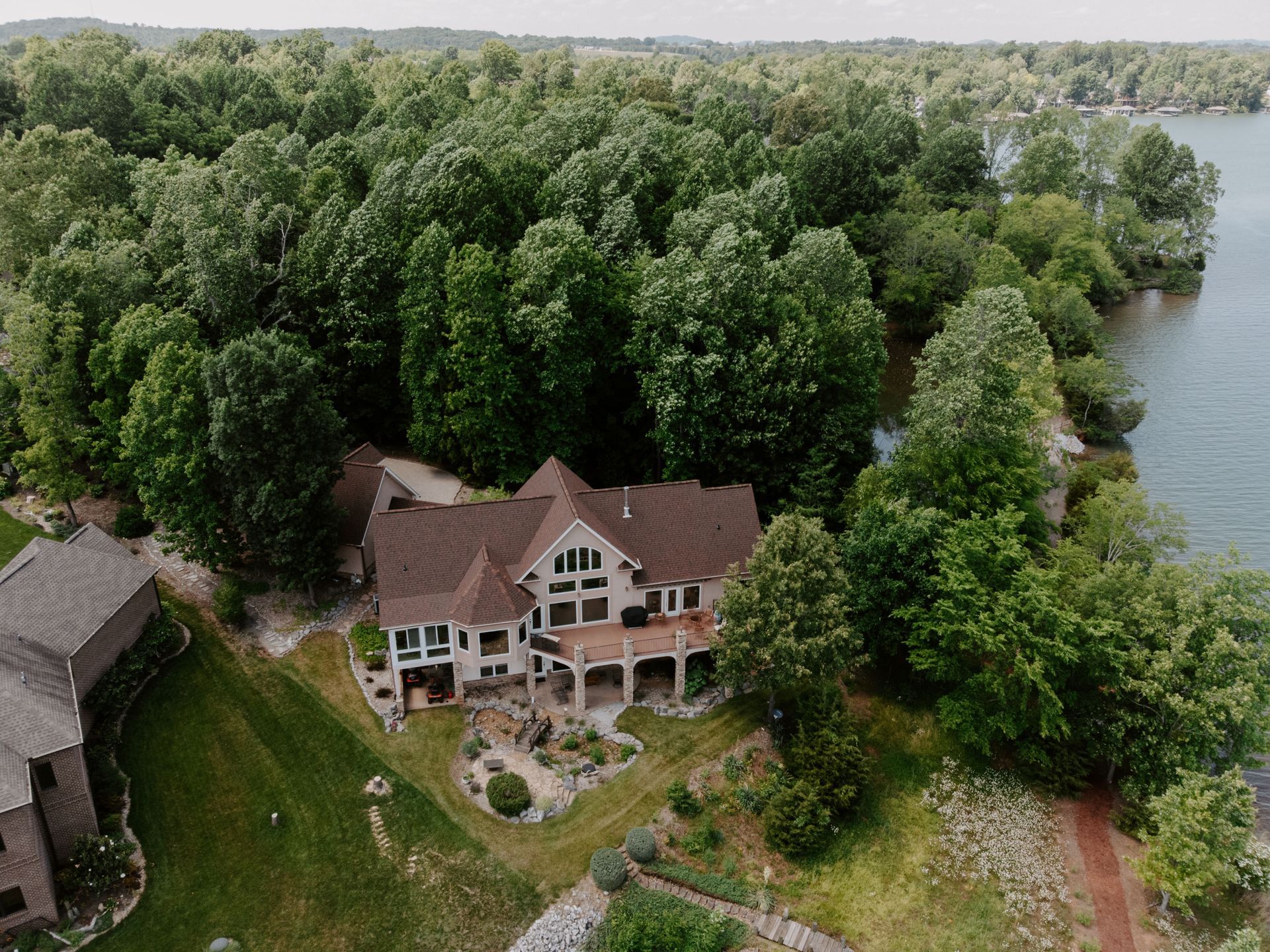 An aerial view of a large house surrounded by trees and a lake.
