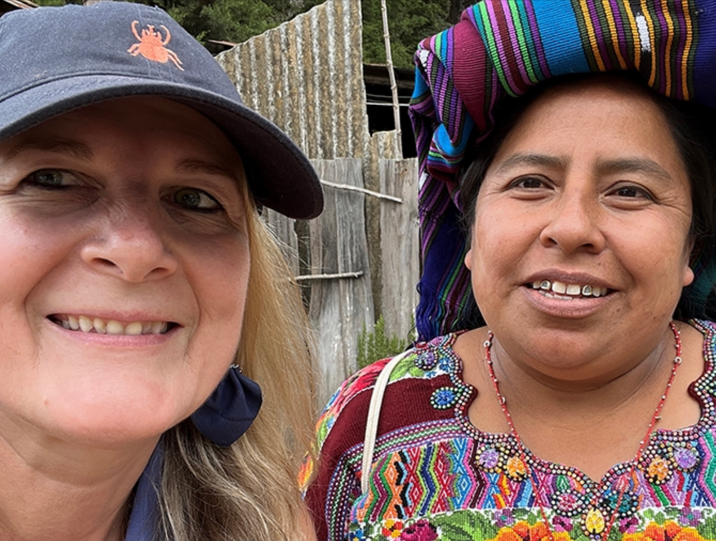 Two women are posing for a picture and one is wearing a hat.