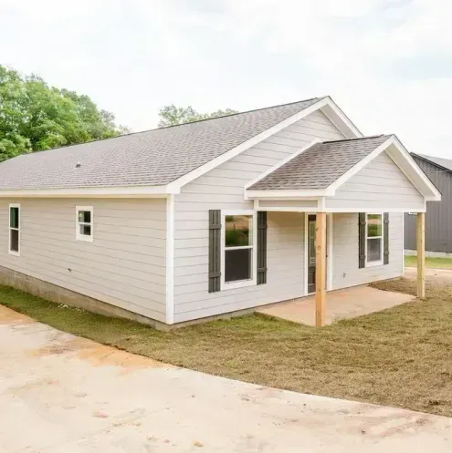 A small white house with black shutters and a porch.