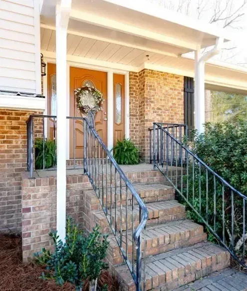 A brick house with stairs leading up to the front door