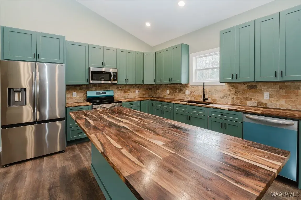 A kitchen with green cabinets and stainless steel appliances