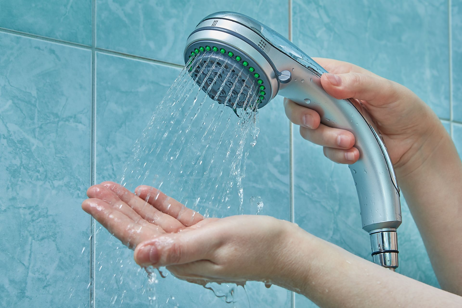 A person is holding a shower head with water coming out of it