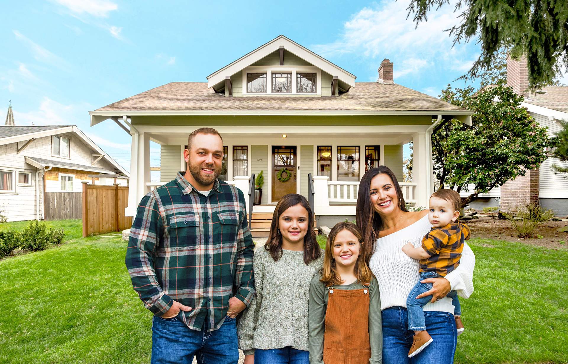 A family is posing for a picture in front of their house.