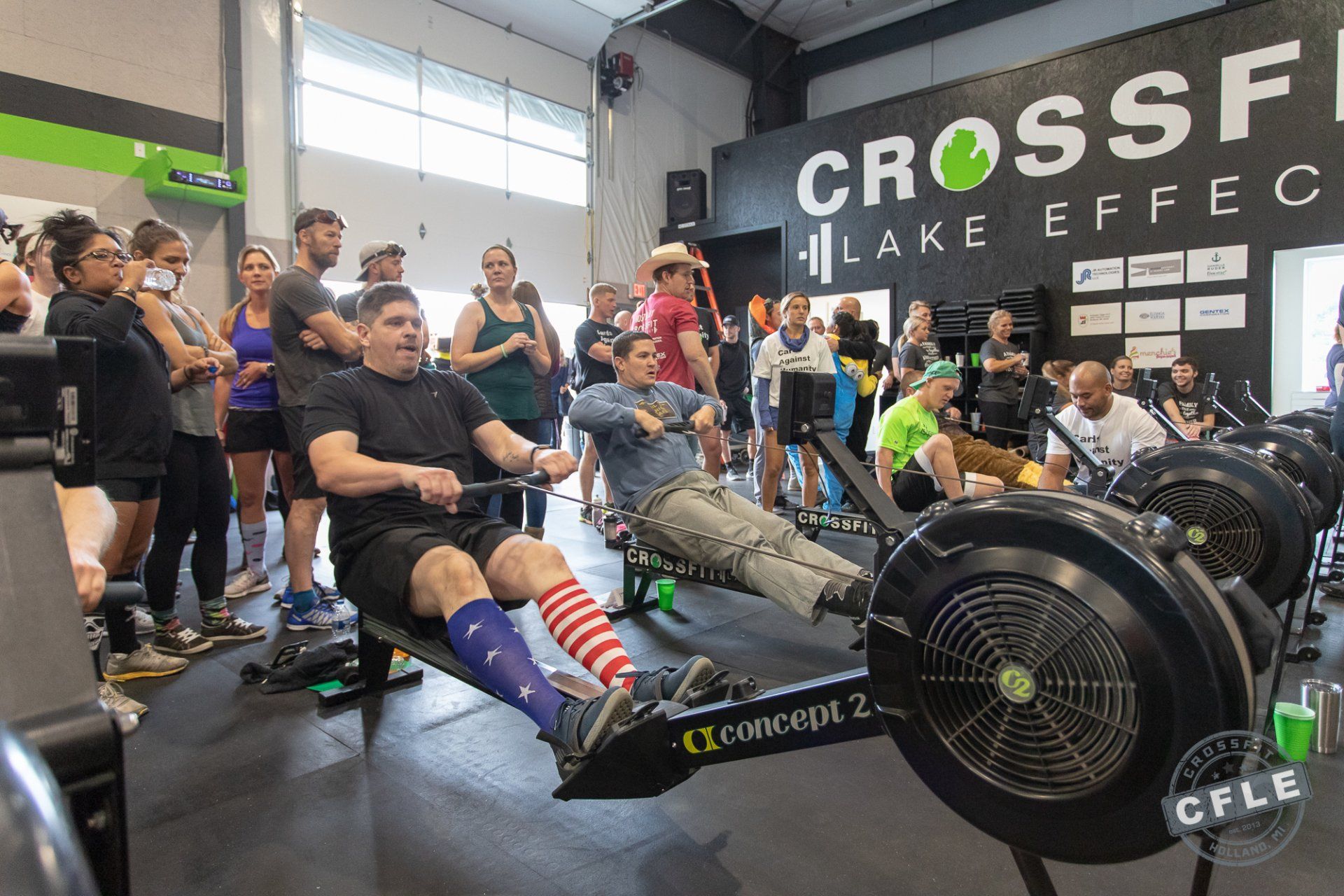 A group of people are sitting on rowing machines in a gym.