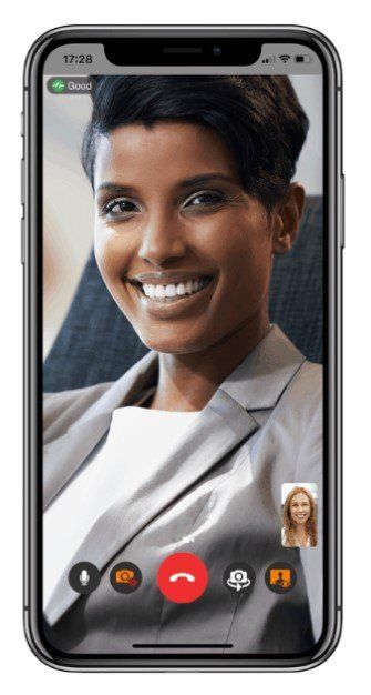 Woman smiling on a video call on a smartphone. A small video view of another person is visible.