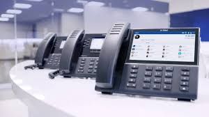 A row of telephones sitting on top of a white table in an office.