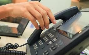 A person is pressing a button on a telephone.