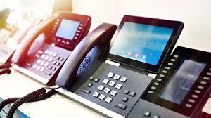 A row of telephones sitting on top of a desk.