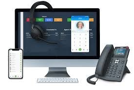 A computer , phone , headphones and a cell phone are sitting next to each other.