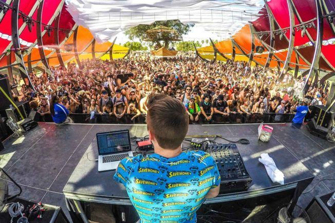 DJ Playing Festival Behind Large Crowd