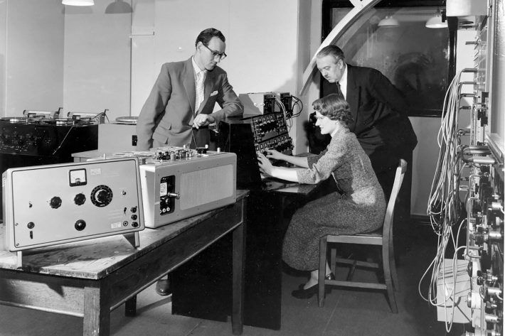 A black and white photo of three people working on a machine