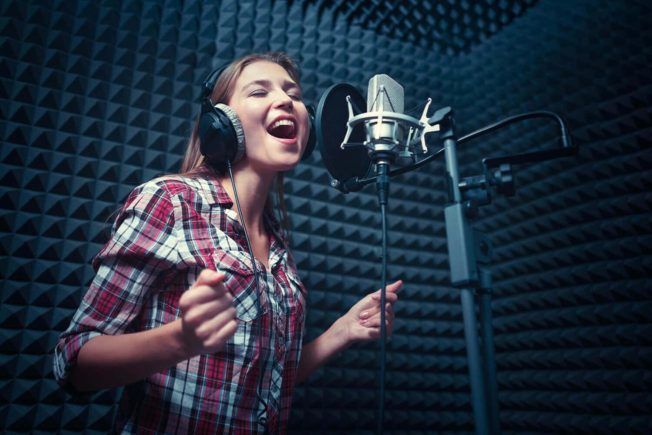 women singing in vocal booth in recording studio