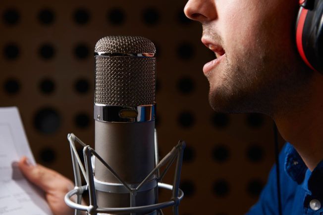 A man wearing headphones is singing into a microphone.