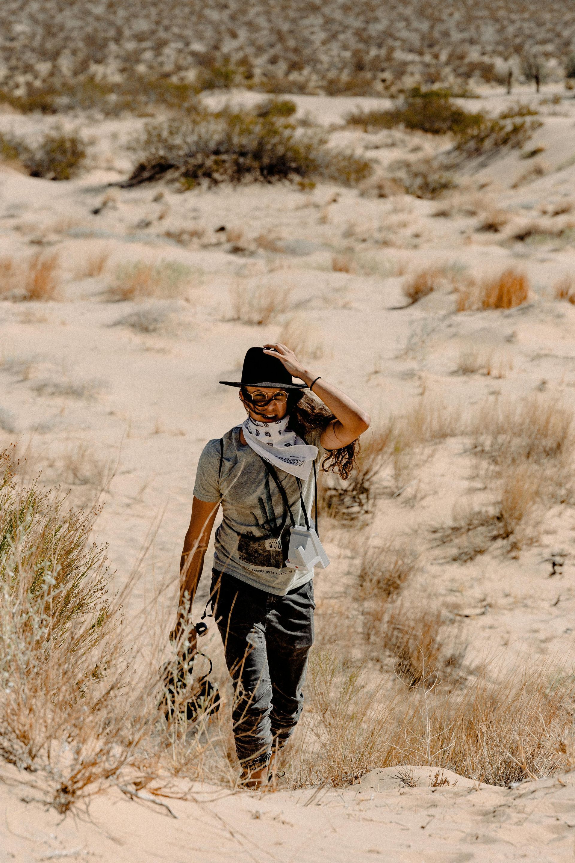Lioness stands in tall grass, looking to the left. Golden light bathes her coat, with a backdrop of trees.