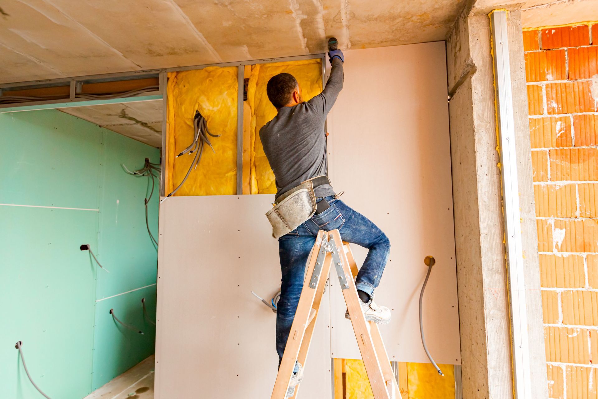 A man is standing on a ladder in a room.