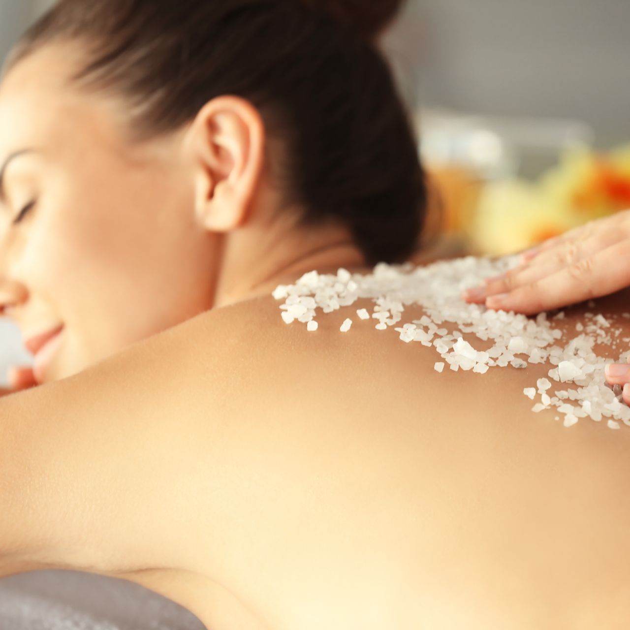 A woman is getting a massage with sea salt on her back