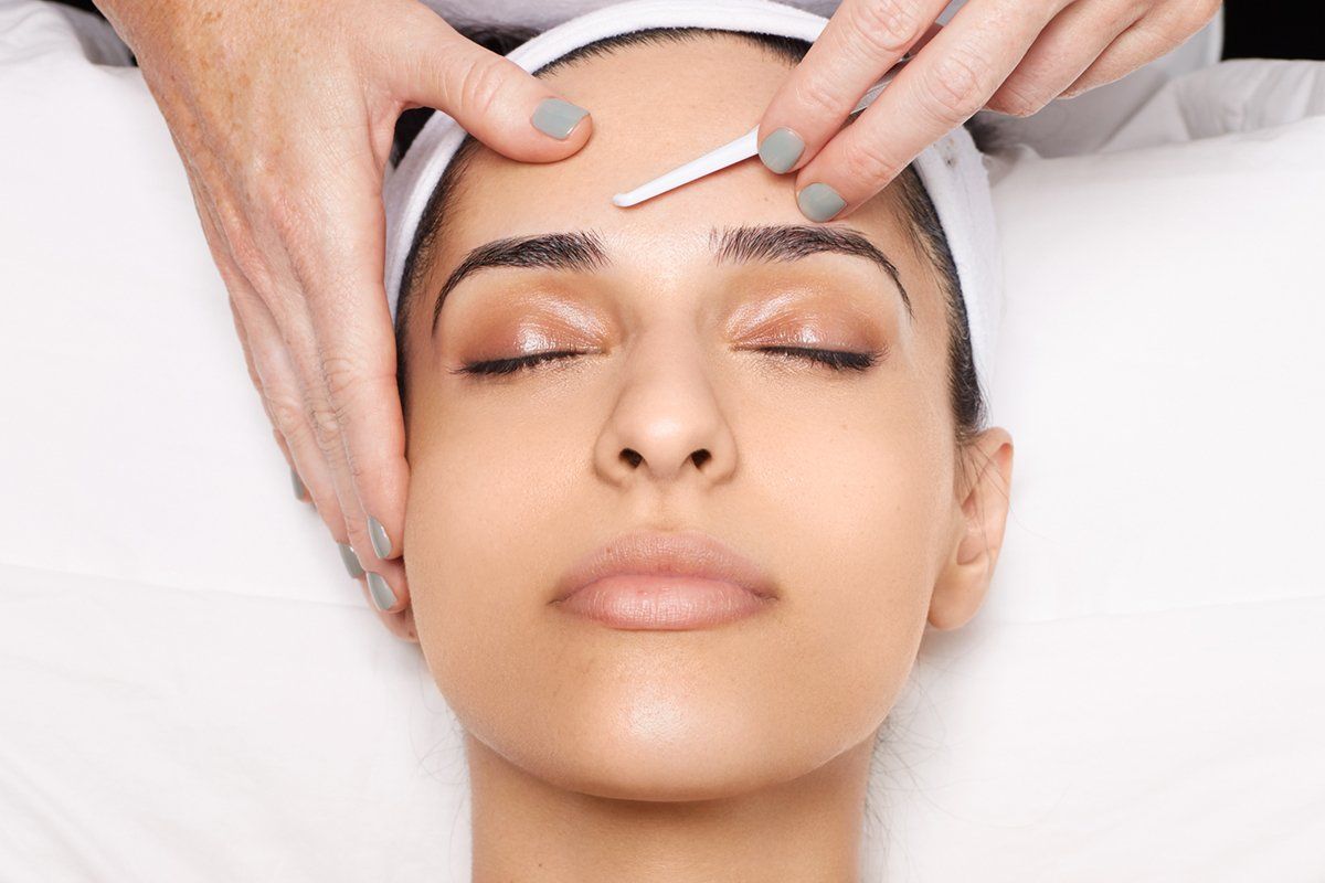 A woman is getting her eyebrows waxed at a beauty salon.