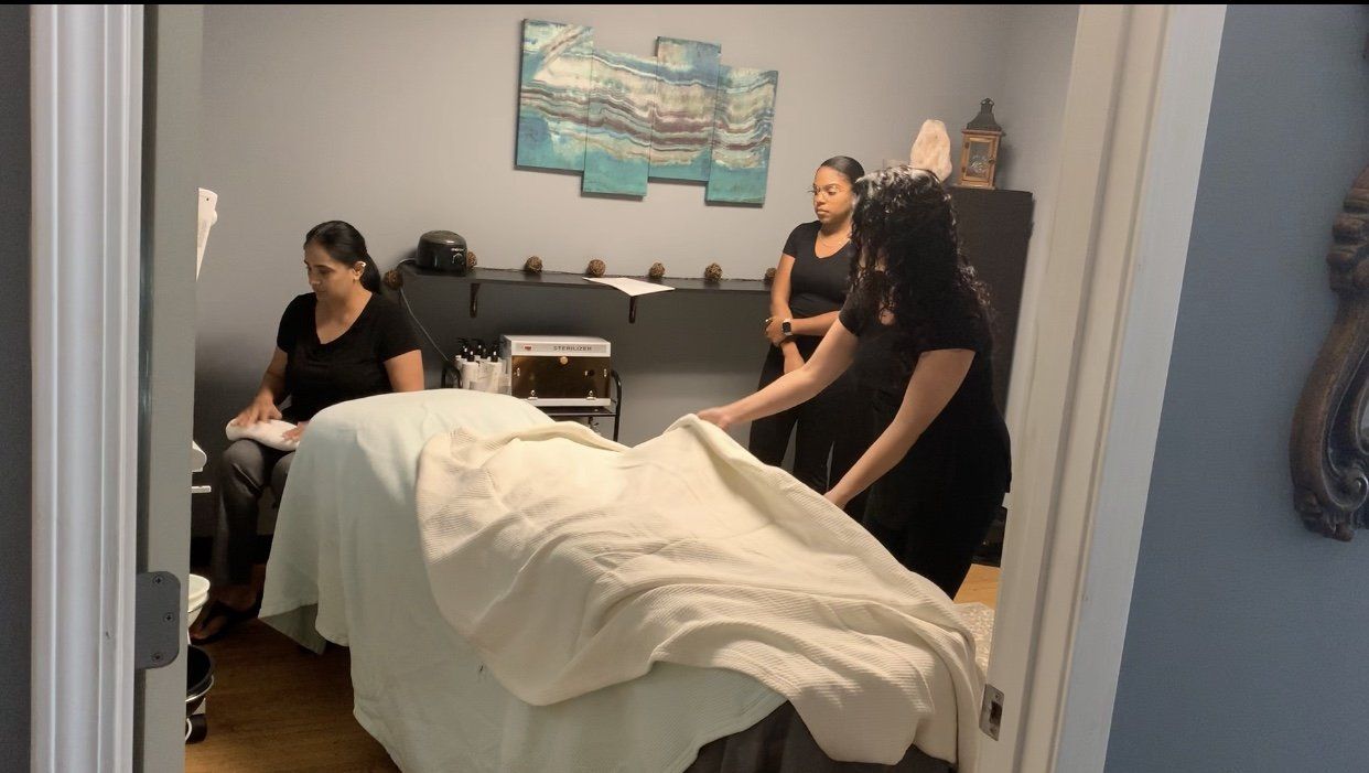 A group of women are standing around a massage table in a room.