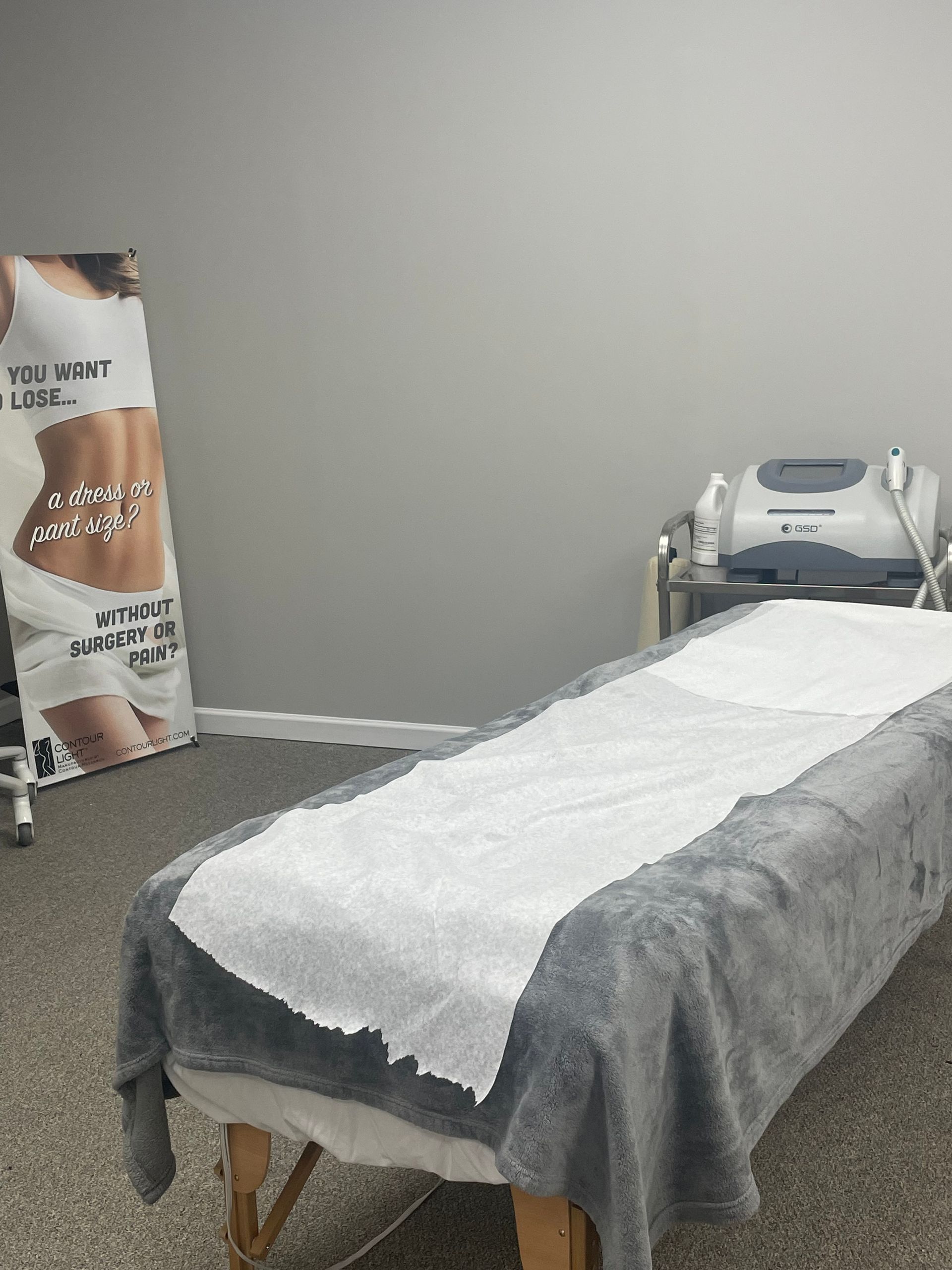 A massage table in a room with a picture of a woman on the wall.