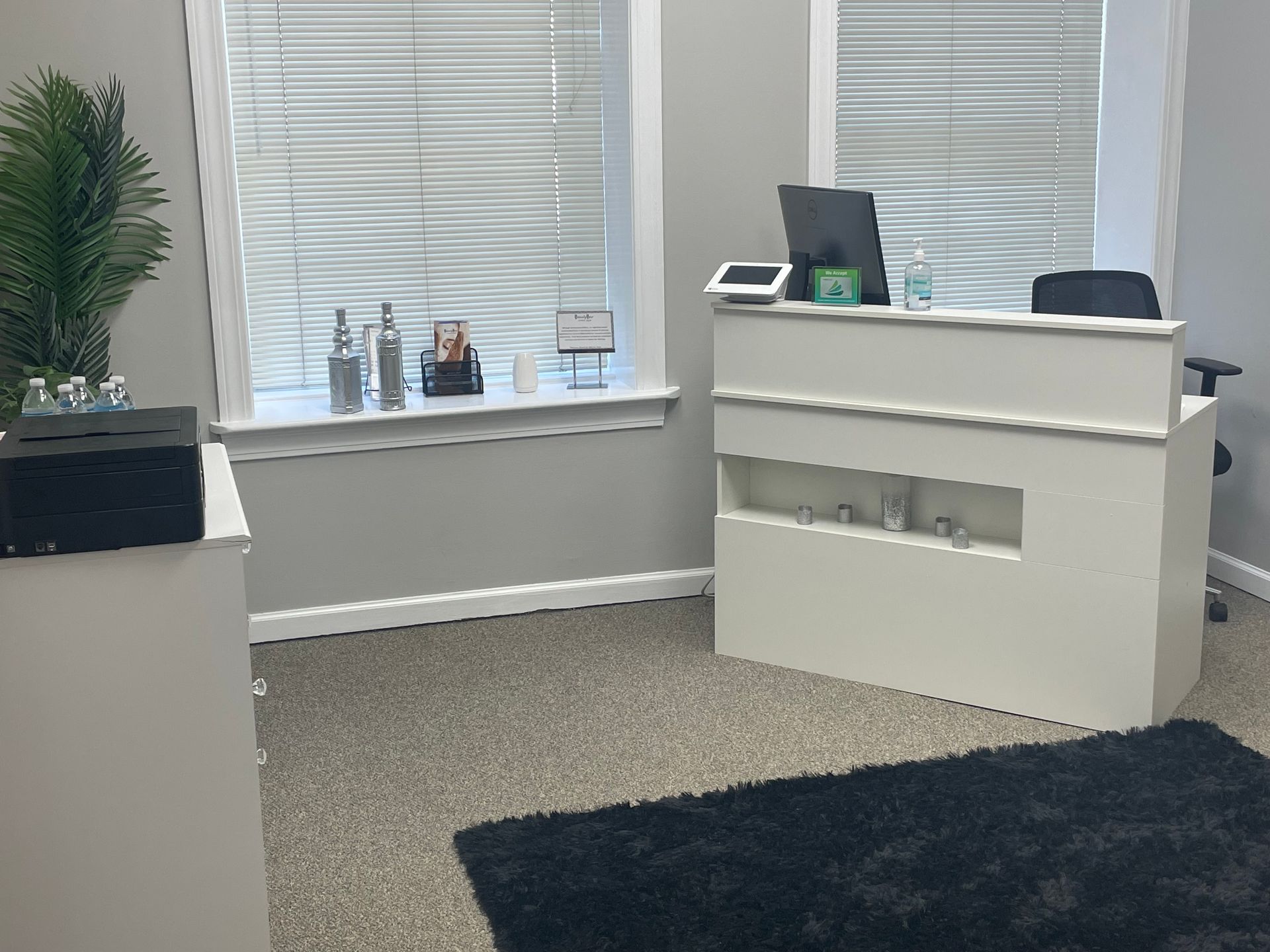 A room with a desk and a window with blinds.