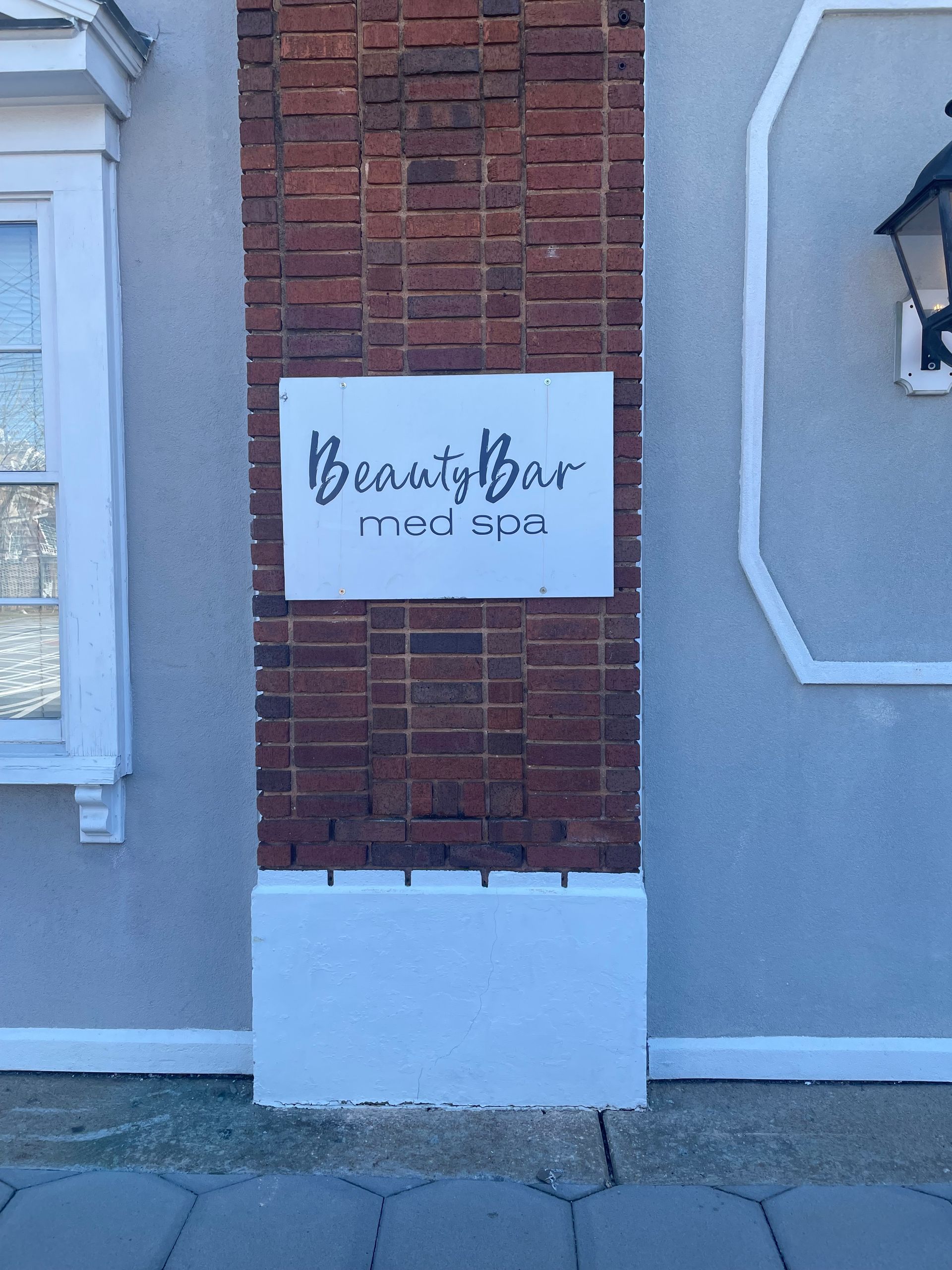 A white sign on a brick wall says beauty bar med spa