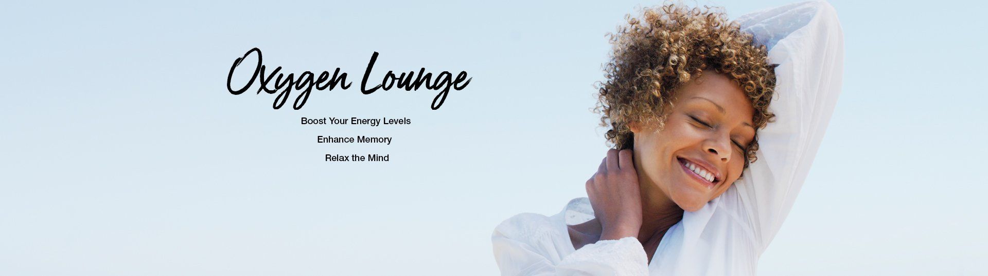 A woman with curly hair is smiling in front of a sign that says oxygen lounge