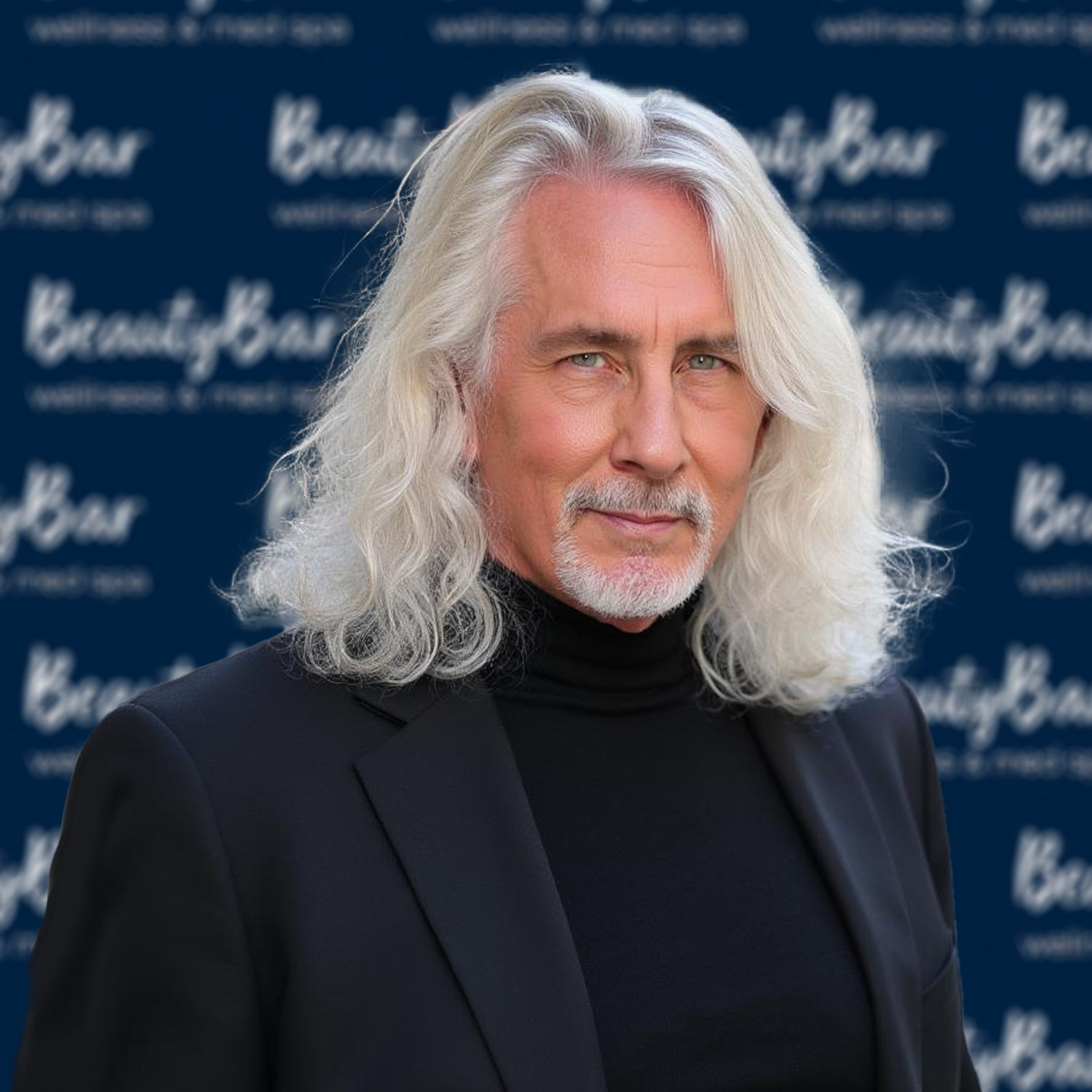 A man with gray hair and a beard is smiling for the camera.